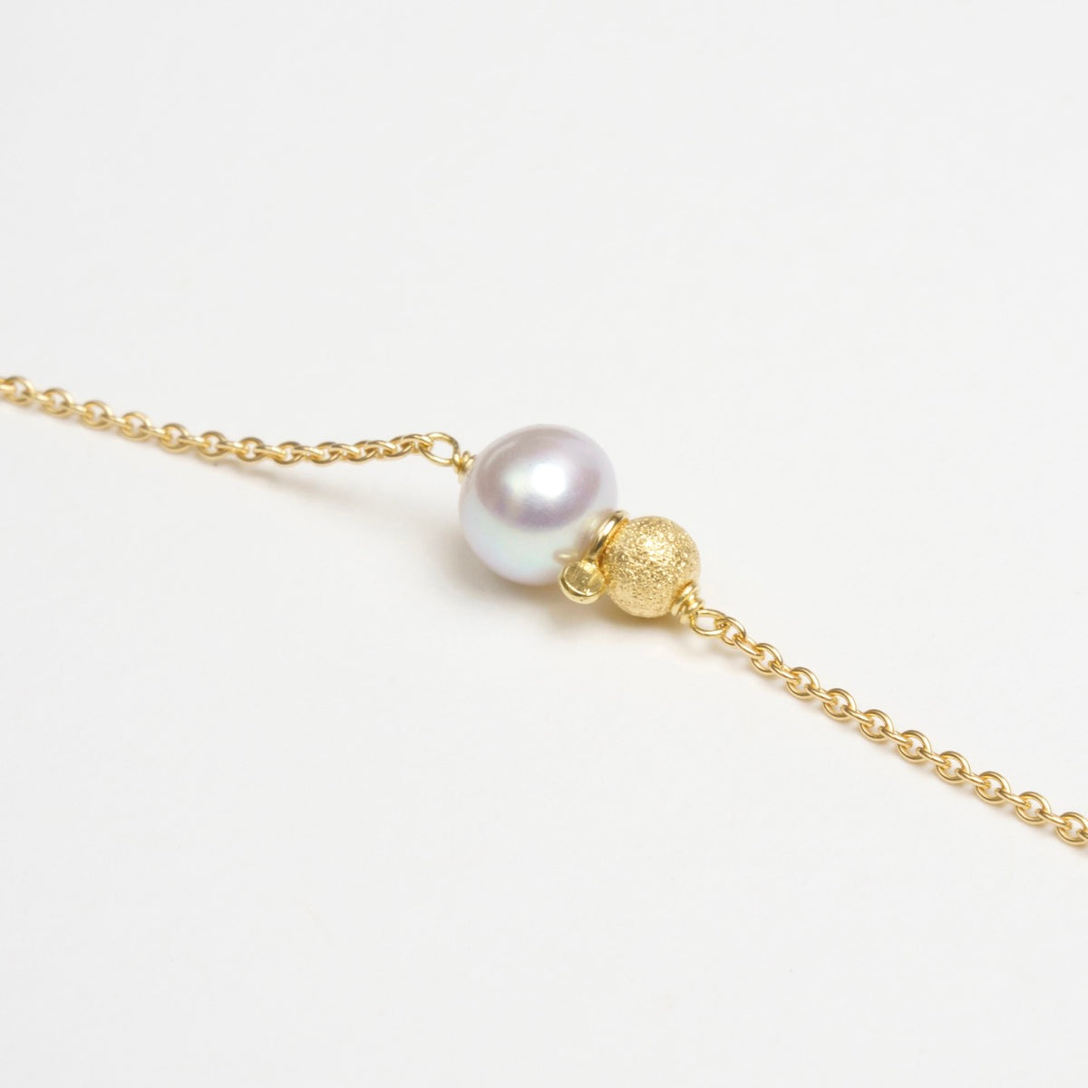 Delicate Saltwater Bracelet featuring a 6.5mm freshwater pearl and a gold glitter ball, on an 18ct yellow gold chain.