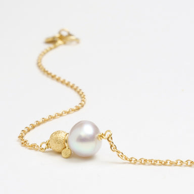 Gold bracelet featuring a 6.5mm freshwater pearl, a gold glitter ball, and delicate chain links.