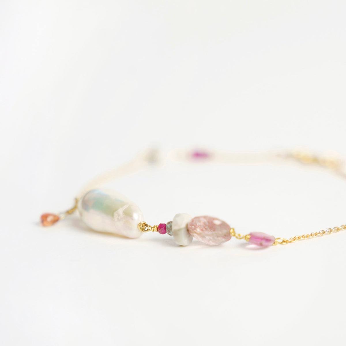 Bronzewing Bracelet 1 features a mix of gemstones, including a baroque pearl, orange sapphire, and pink sapphire, on a gold chain.