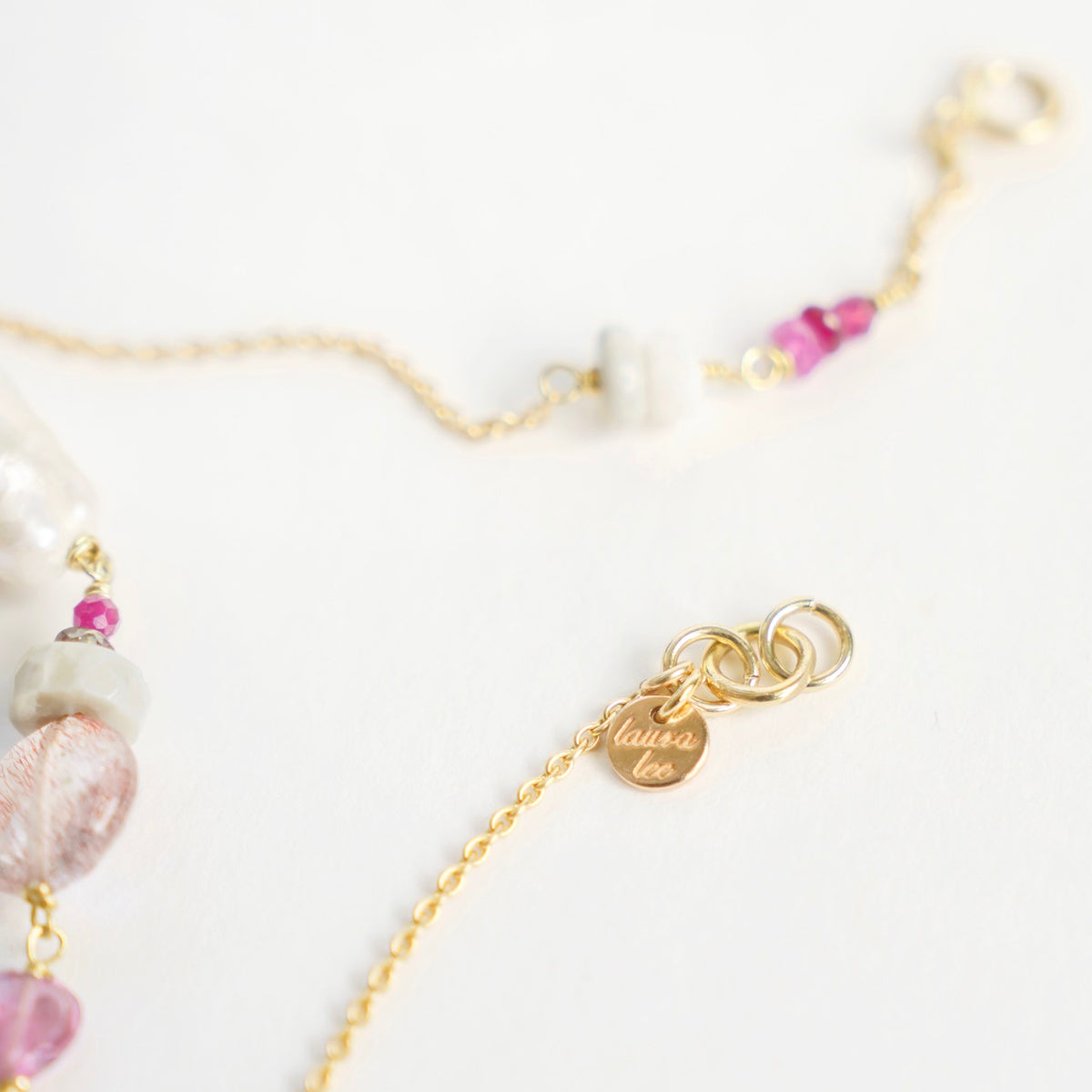 Yellow gold chain bracelet featuring unique gems, including freshwater baroque pearl, pink sapphire, and tourmaline heart.