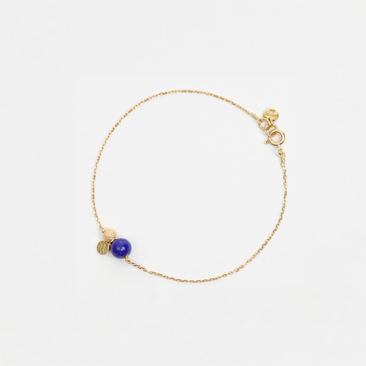 Delicate 18ct yellow gold chain bracelet featuring a rich lapis lazuli stone, gold sparkle bead, and textured gold sequin.