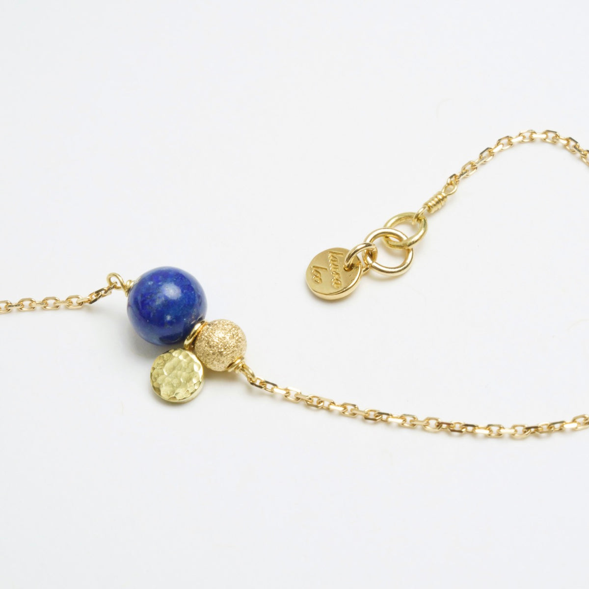 Delicate gold chain bracelet featuring a rich blue Lapis Lazuli bead, a sparkling gold bead, and a textured gold sequin.