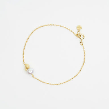 Delicate 18ct yellow gold trace chain bracelet featuring a 6.5mm freshwater pearl and a 4mm gold glitter ball.