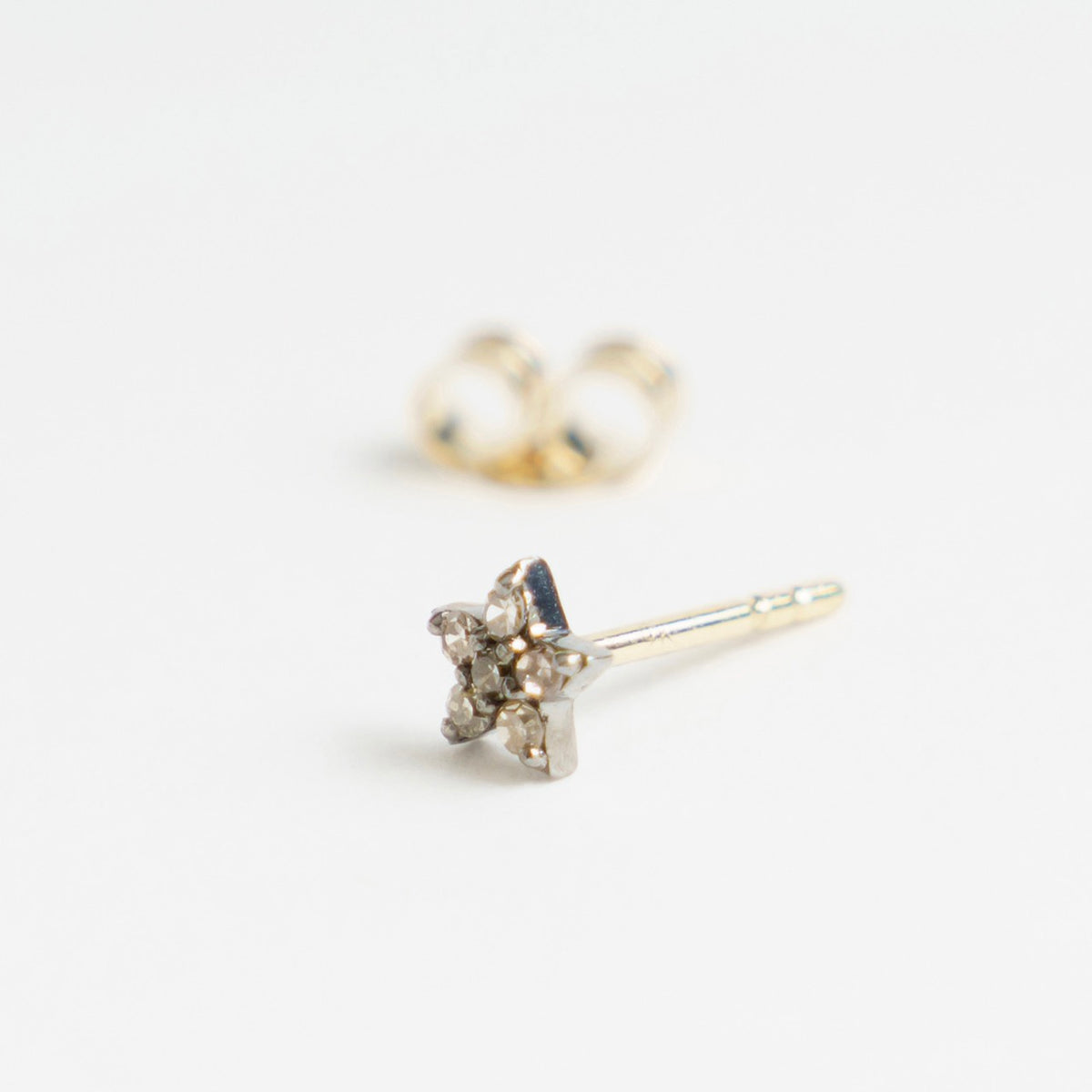 Silver star-shaped earrings featuring salt and pepper diamonds, with a 9ct yellow gold post.
