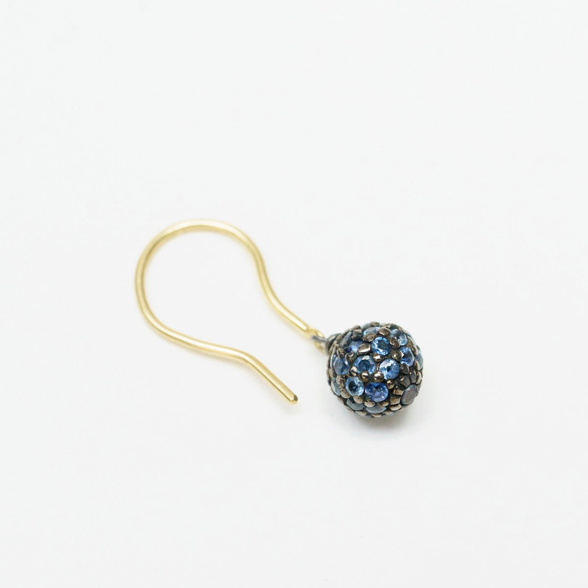 Sapphire Stardust Drop Earrings feature a round blackened silver bead adorned with blue sapphires, complemented by an 18ct yellow gold hook.