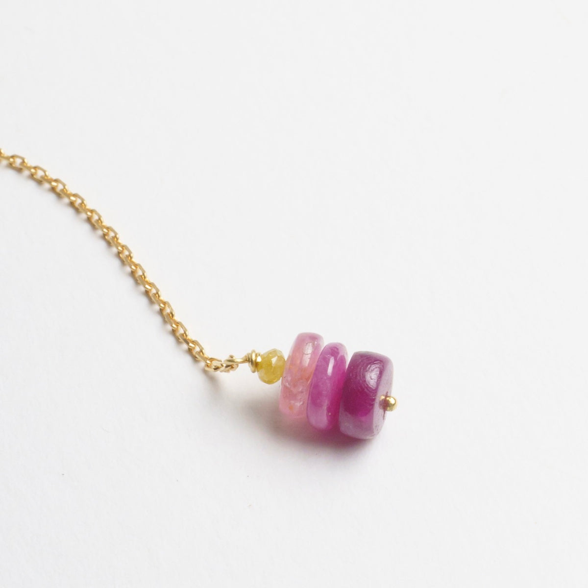 Raspberry-toned sapphire beads threaded on a fine 18ct yellow gold chain, showcasing a playful drop design.
