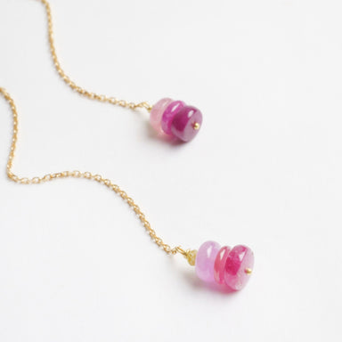 Thread-through earrings featuring 18ct yellow gold chains with raspberry-toned sapphire beads in shades of pink.