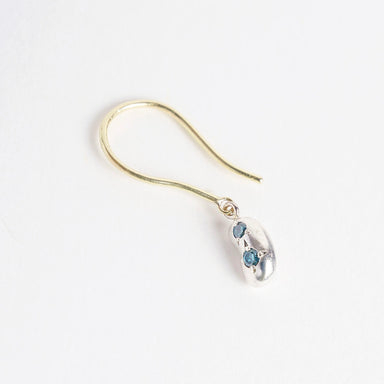 Mini Bean Drops earrings feature a silver bean design with two teal diamonds, suspended from 18ct yellow gold hooks.
