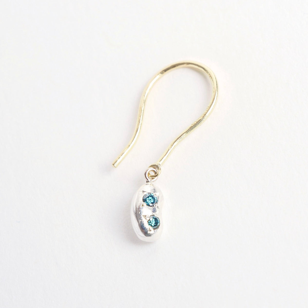 Sterling silver earrings shaped like a bean, featuring two teal diamond accents and 18ct yellow gold hooks.