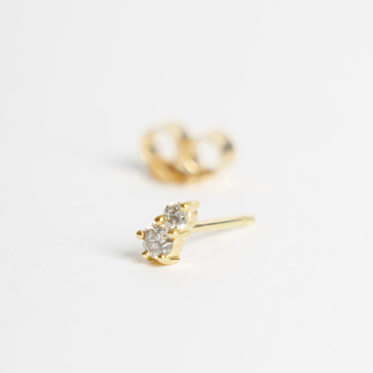 Two sparkling silver diamond studs set in 18ct yellow gold, showcasing a minimalist design with a classic appeal.