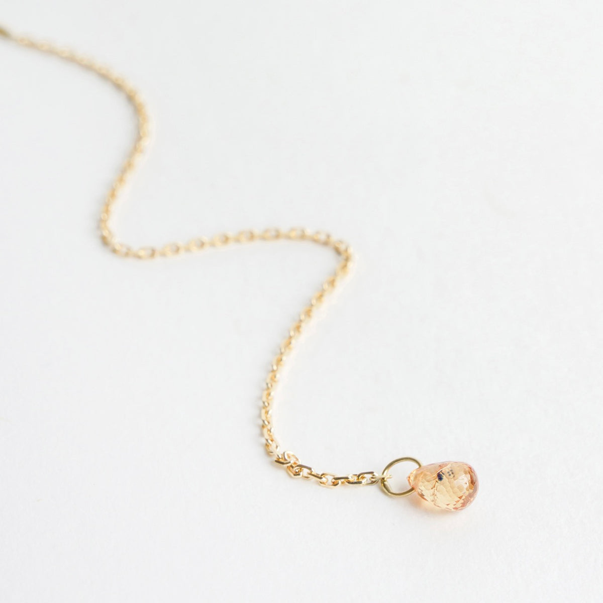 18ct yellow gold earrings featuring a delicate chain with a faceted 3D sapphire briolette at the end.