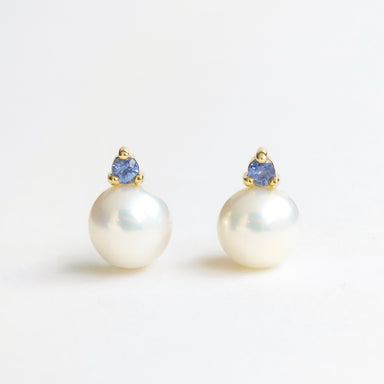 Lustrous freshwater pearl earrings featuring a blue sapphire and 18ct yellow gold setting.