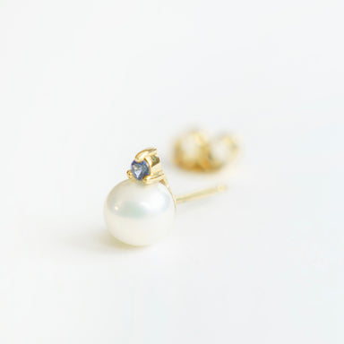 Lustrous 6mm freshwater pearl earrings in 18ct yellow gold, featuring a blue sapphire accent on top.