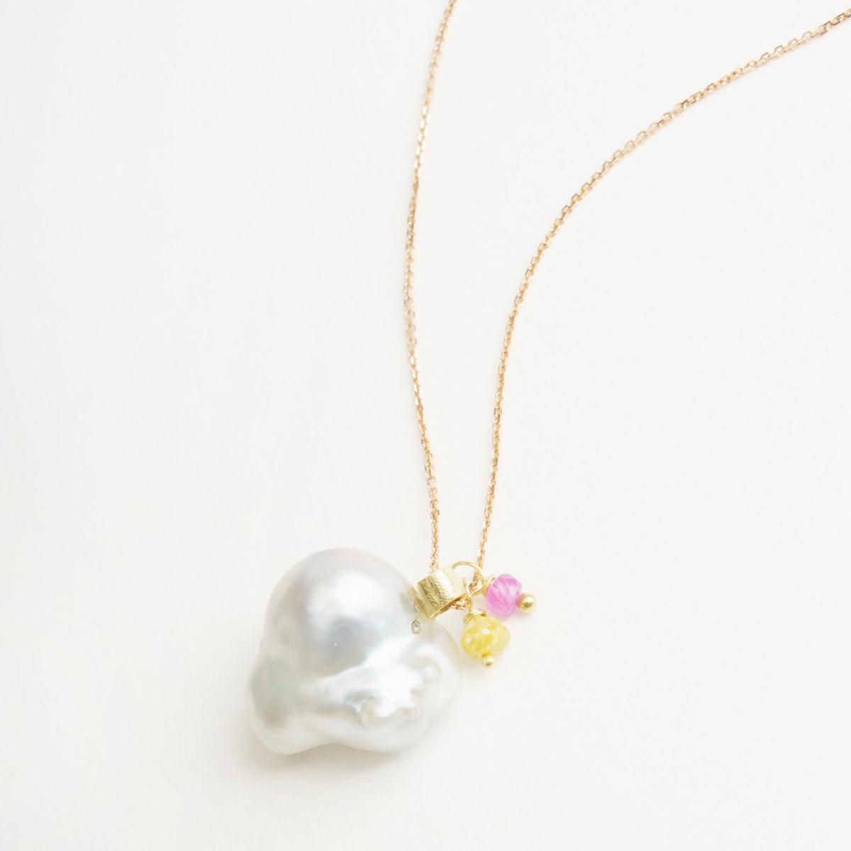 Heart-shaped South Sea pearl pendant in 18ct rose gold with yellow gold bail, featuring pink tourmaline and yellow diamond accents.