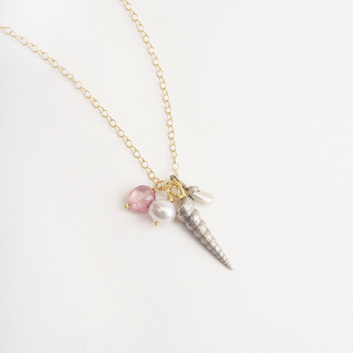 Silver Larrakia Shell pendant on a yellow gold chain, with lilac freshwater pearl and pink tourmaline beads.