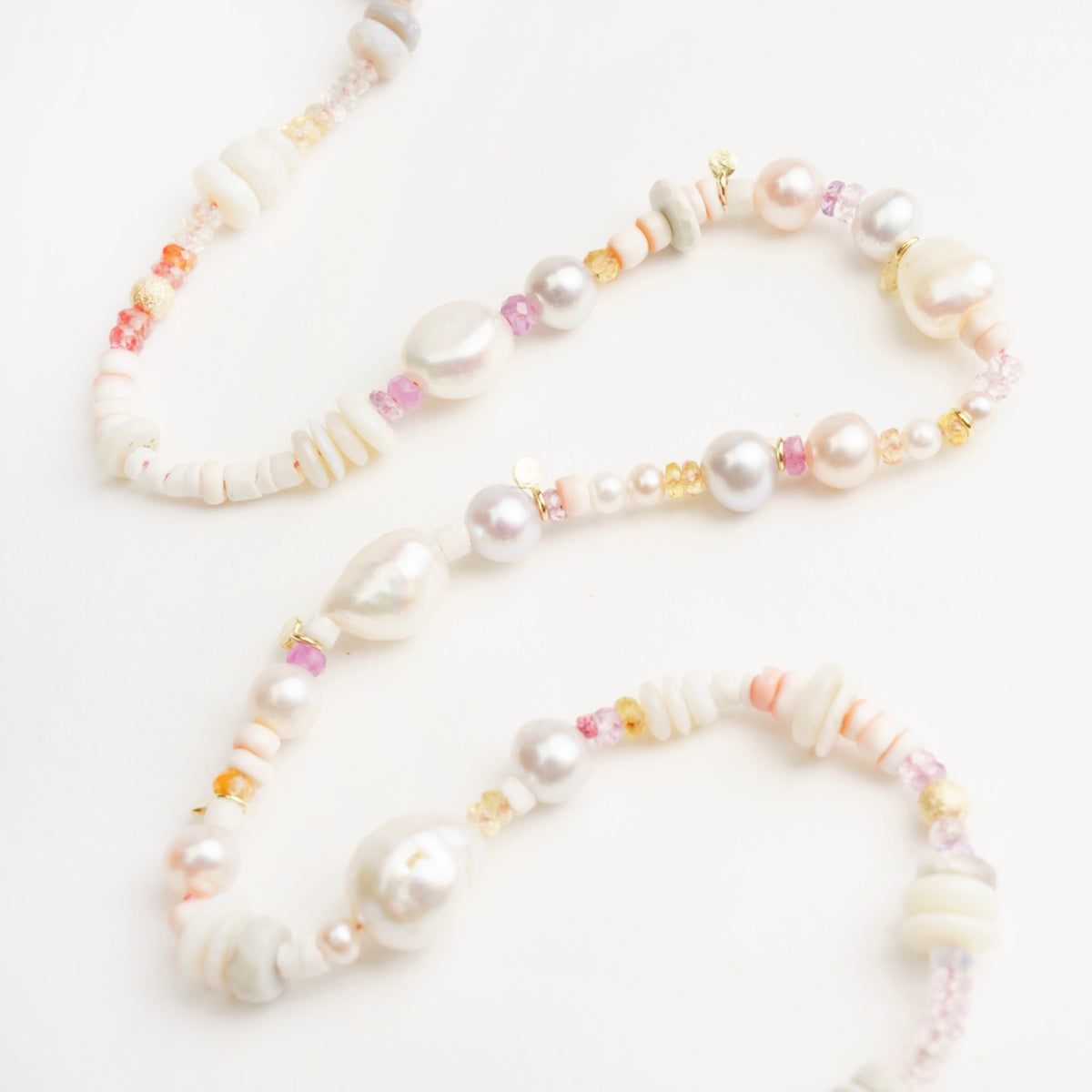 Delicate Corella Choker featuring white and lavender pearls, colorful sapphires, and gold accents, arranged elegantly.