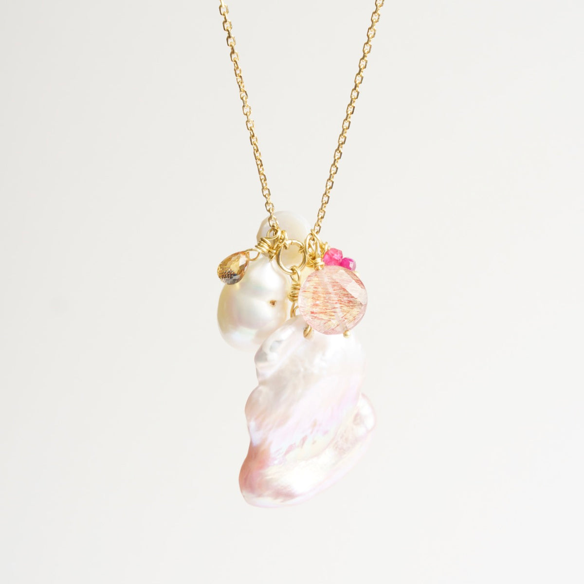 Cluster necklace featuring large organic pink pearls, orange sapphire, and citrine on a delicate 18ct yellow gold chain.