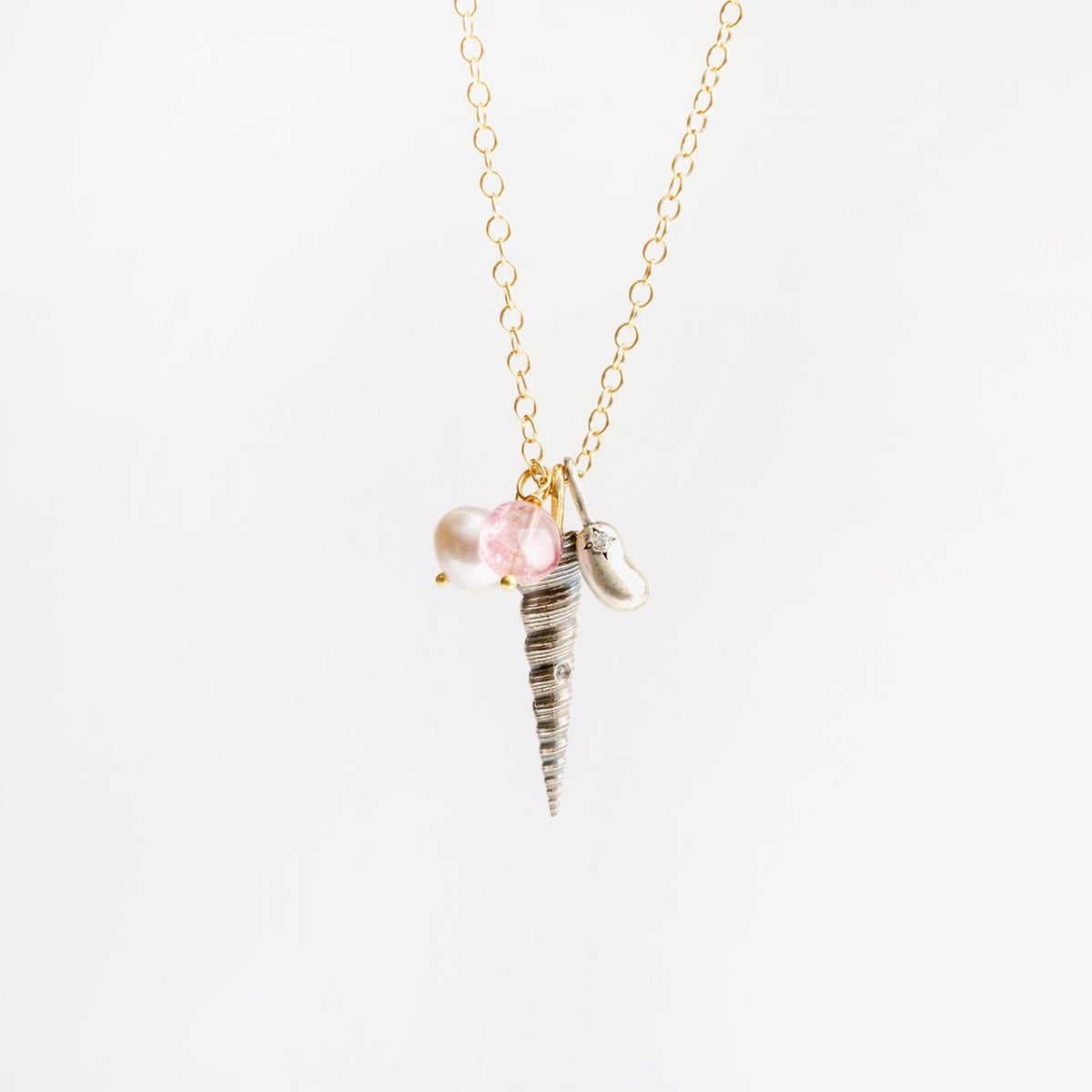 Larrakia Shell Cluster Necklace featuring a silver shell pendant, pink tourmaline and freshwater pearl beads on a gold chain.