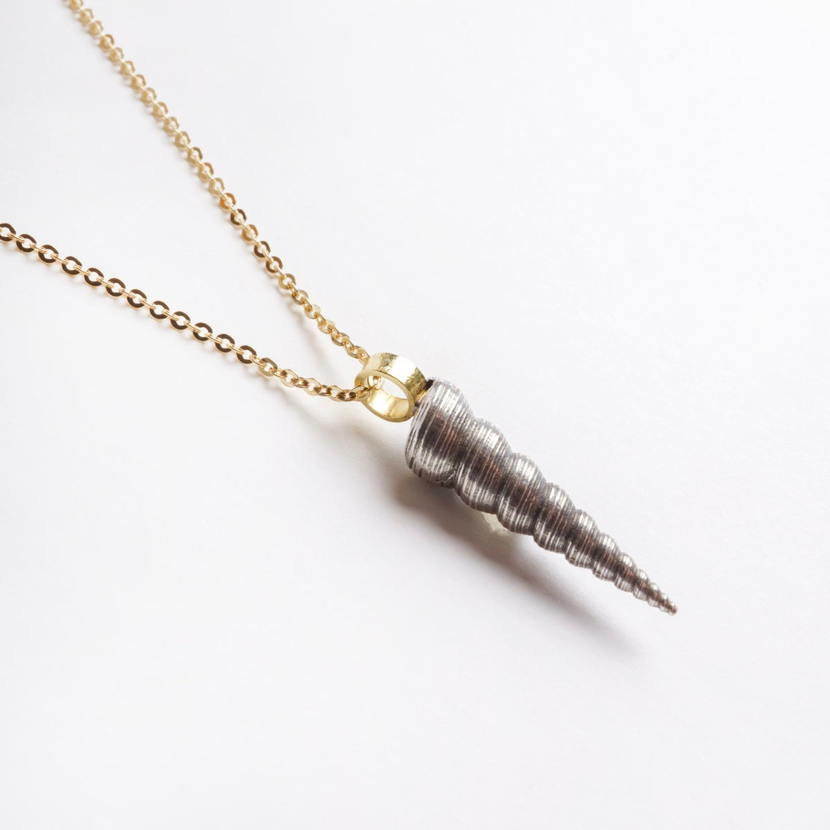 Sterling silver shell pendant with a twist design, hung on an 18ct yellow gold chain.