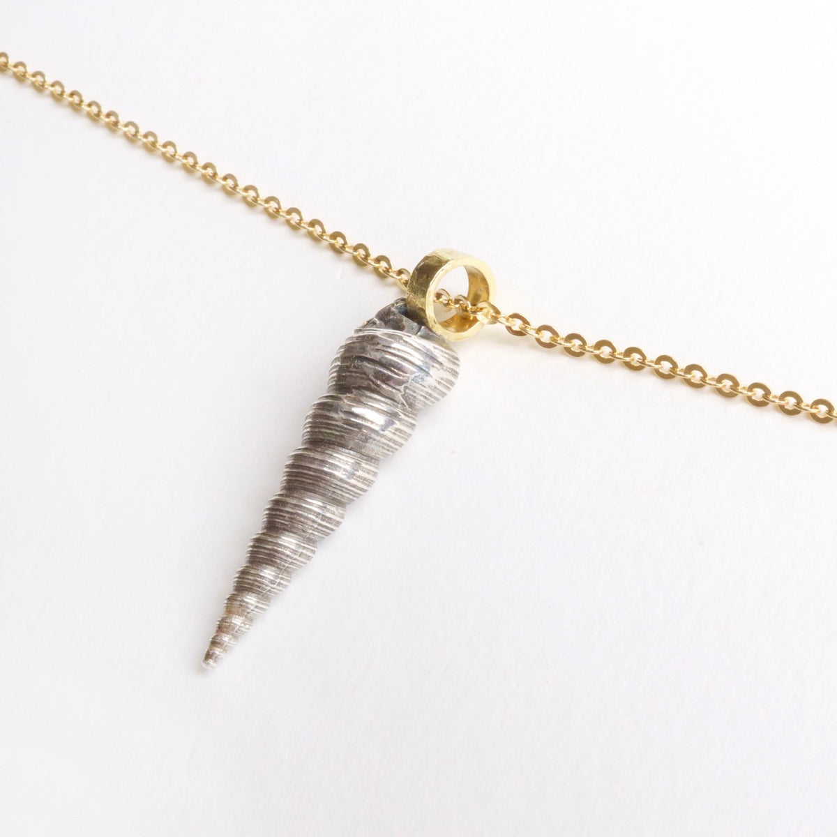 Large Larrakia Shell Pendant featuring a spiraled sterling silver shell with an 18ct gold bail on a delicate gold chain.