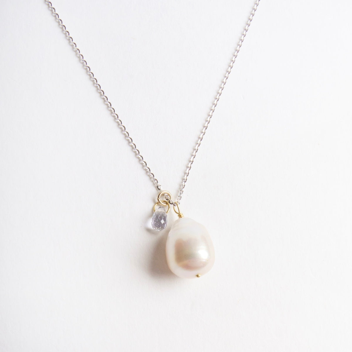 Icy white gold chain necklace featuring a baroque pearl and a blue sapphire drop, accented with yellow gold details.