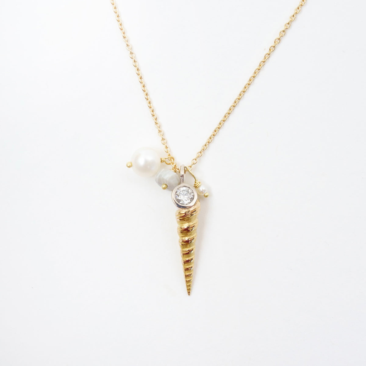 Luxe Larrakia Shell Cluster Necklace featuring a spiral pink gold shell, silver diamond, grey opal, and freshwater pearls.