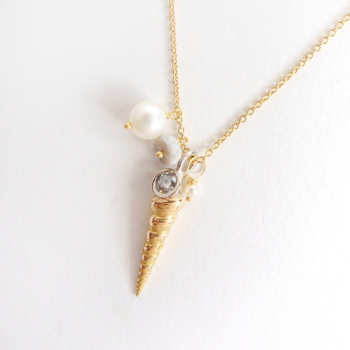 Luxe Larrakia Shell Cluster Necklace features a solid pink gold shell pendant, silver diamond, and pearls on a gold chain.