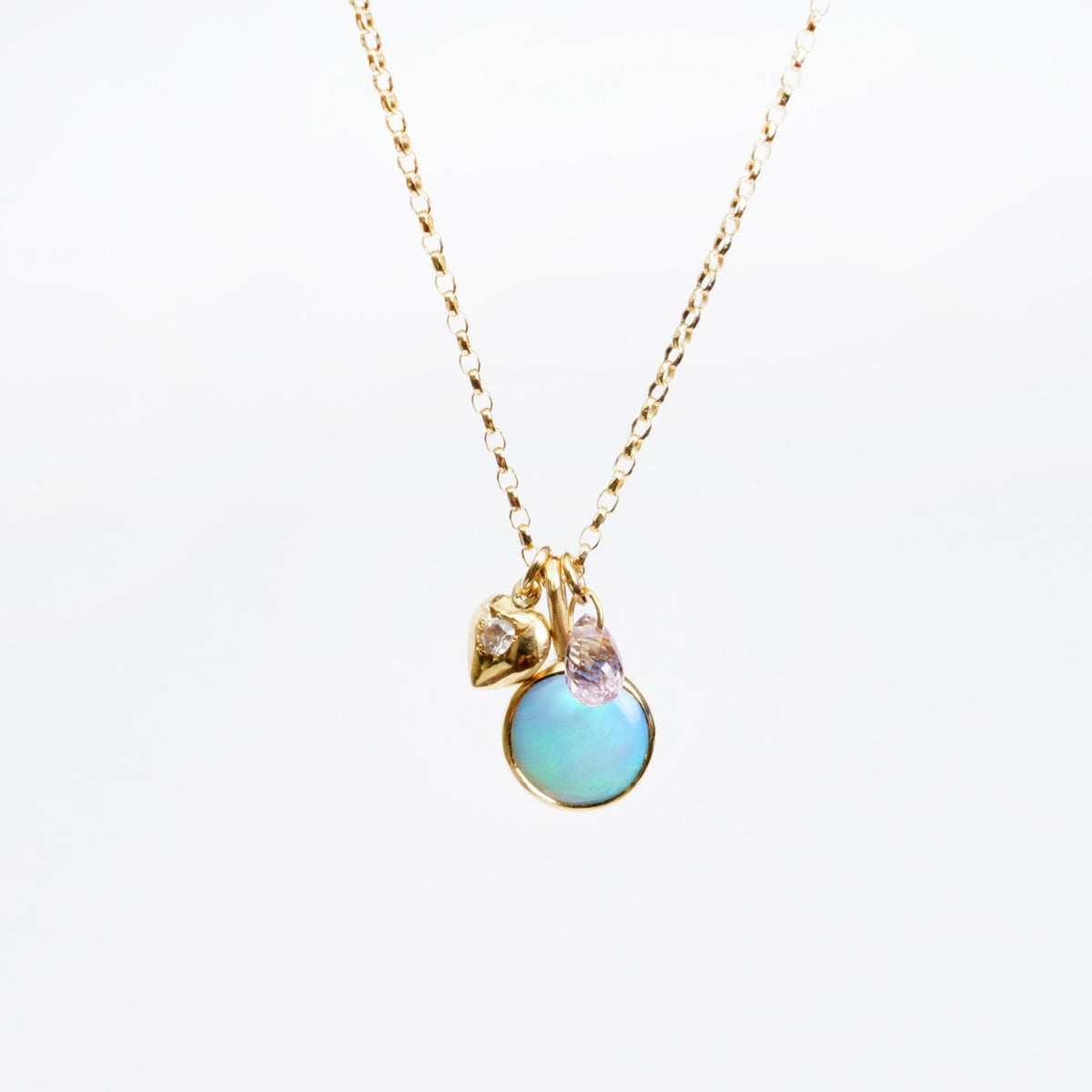 Delicate Saltwater Opal Pendant featuring an 8mm round opal, tiny diamond-set heart, and a blue sapphire briolette on an 18" gold chain.