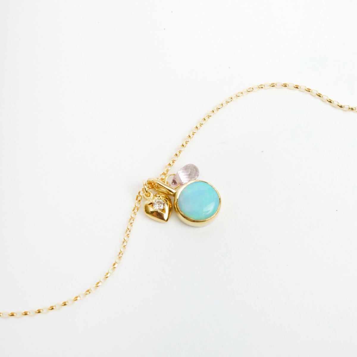 Delicate 18ct yellow gold necklace featuring a round opal, tiny diamond heart, and blue sapphire briolette.
