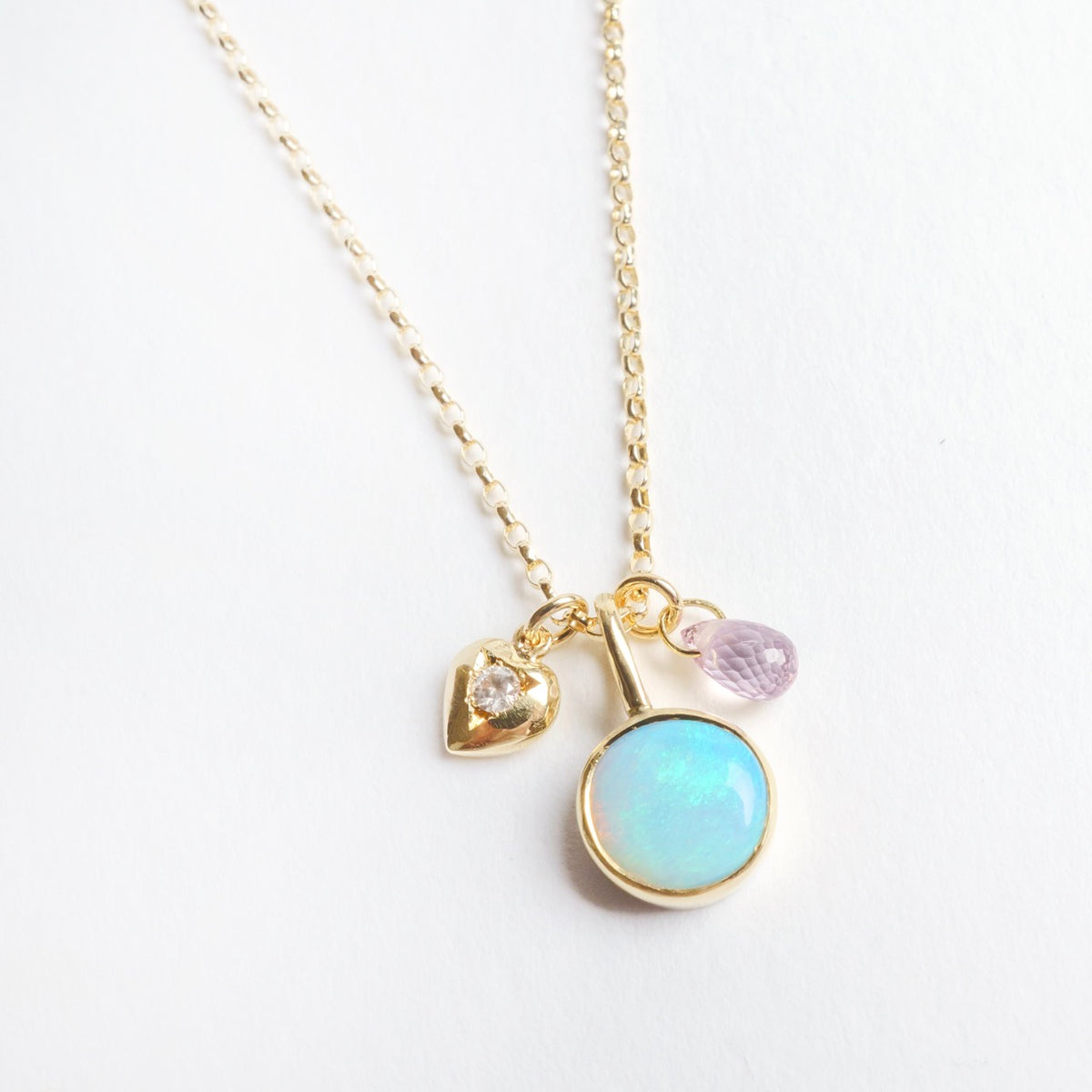 Delicate 18ct yellow gold necklace featuring an 8mm round opal, tiny diamond-set heart, and a blue sapphire briolette.