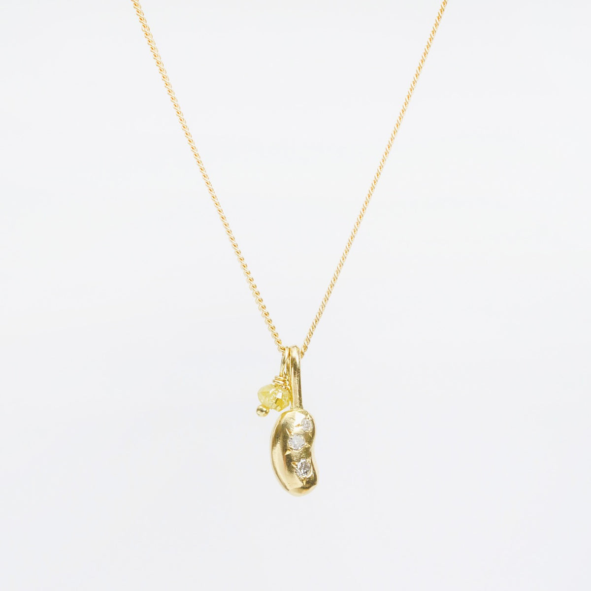 Mini Bean Necklace featuring a gold bean charm with three silver diamonds and a yellow diamond detail, hanging from a flat curb chain.