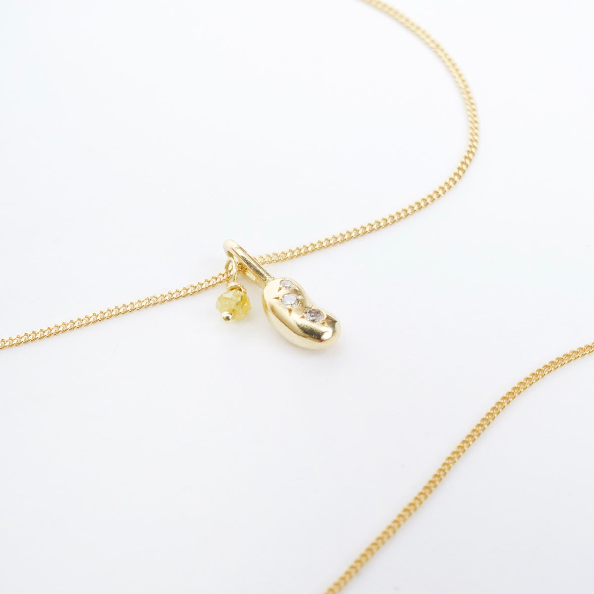 Gold Mini Bean Necklace with three silver diamonds and a yellow diamond charm on a flat curb chain.