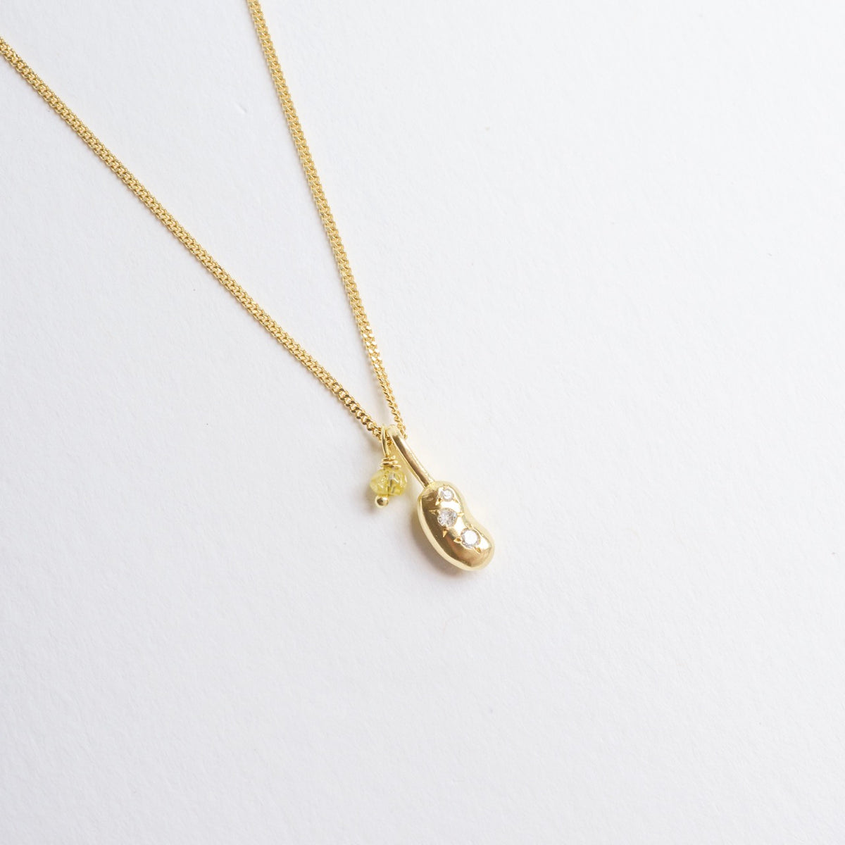 Mini Bean Necklace featuring a tiny gold bean charm with three silver diamonds and a yellow diamond detail on an 18" chain.