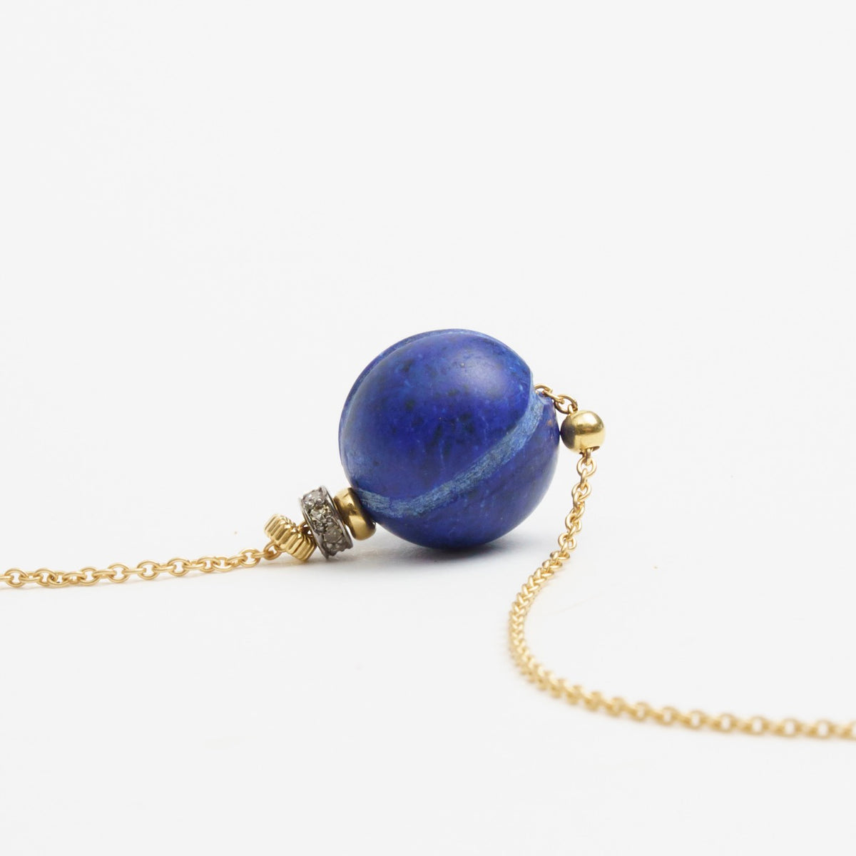 Chic necklace featuring a large, round lapis lazuli bead with gold and diamond accents, hanging from a delicate gold chain.