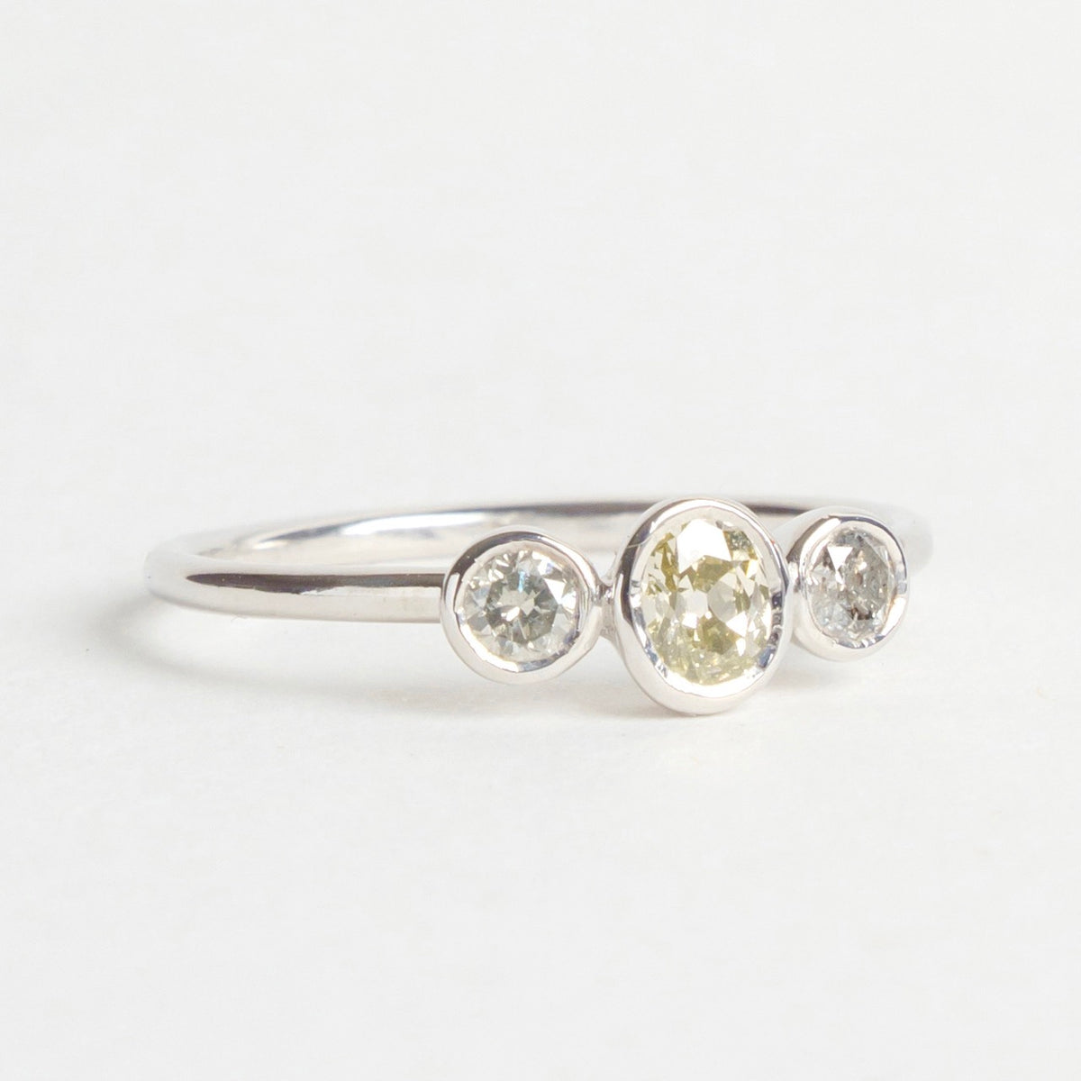 Djulpan Trilogy Ring featuring three mixed-tone diamonds in round and oval shapes set in an 18ct white gold band.