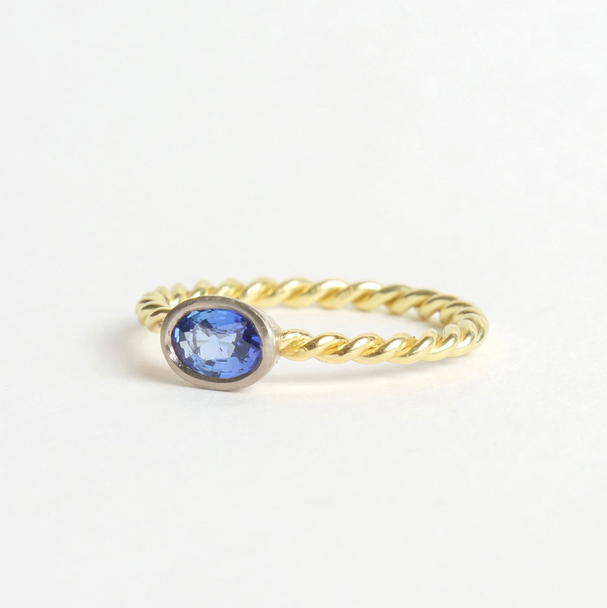 Twisted 18ct yellow gold band with a rich blue sapphire set in a cool white gold bezel.