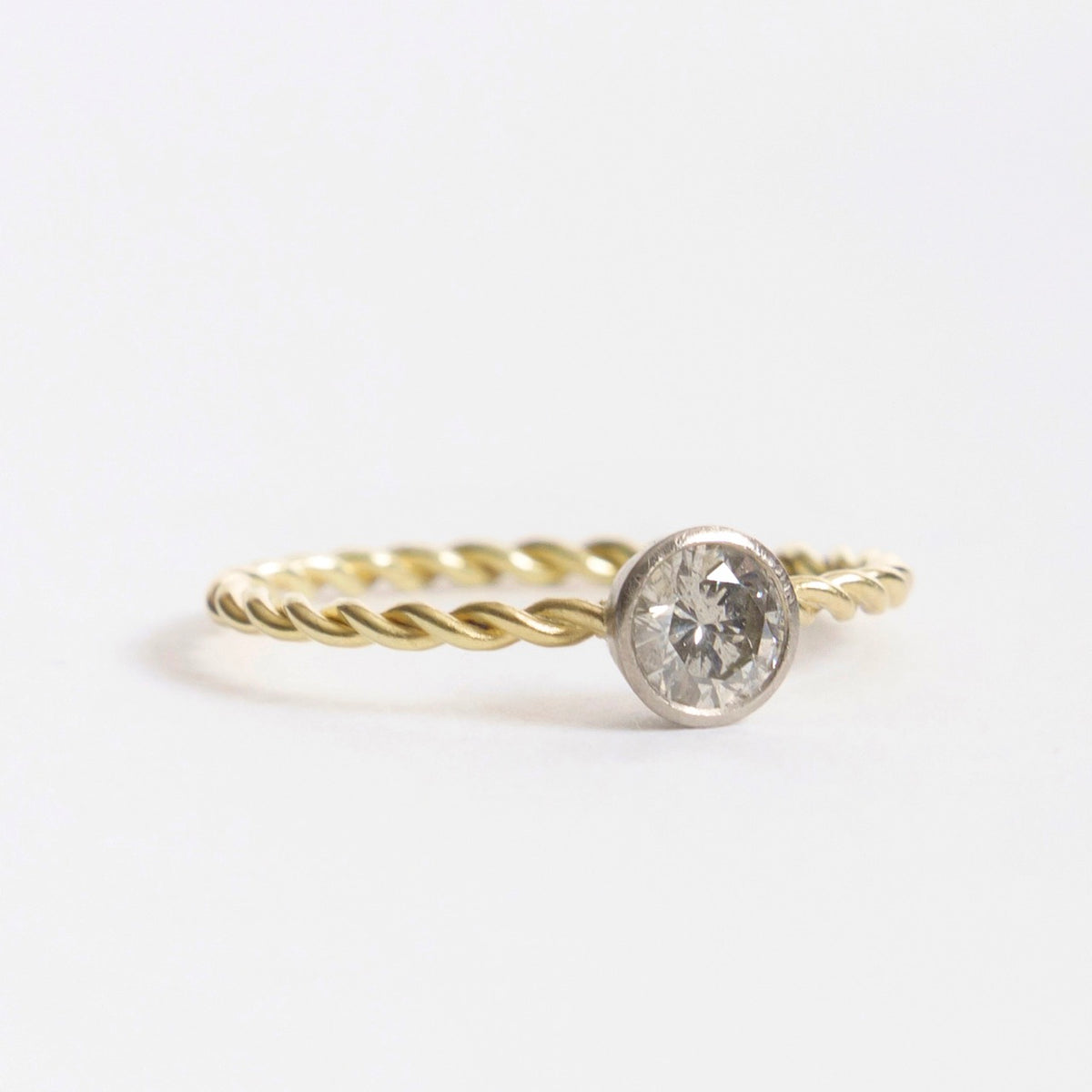 Silver diamond ring featuring a twisted 18ct yellow gold band and a round diamond setting.