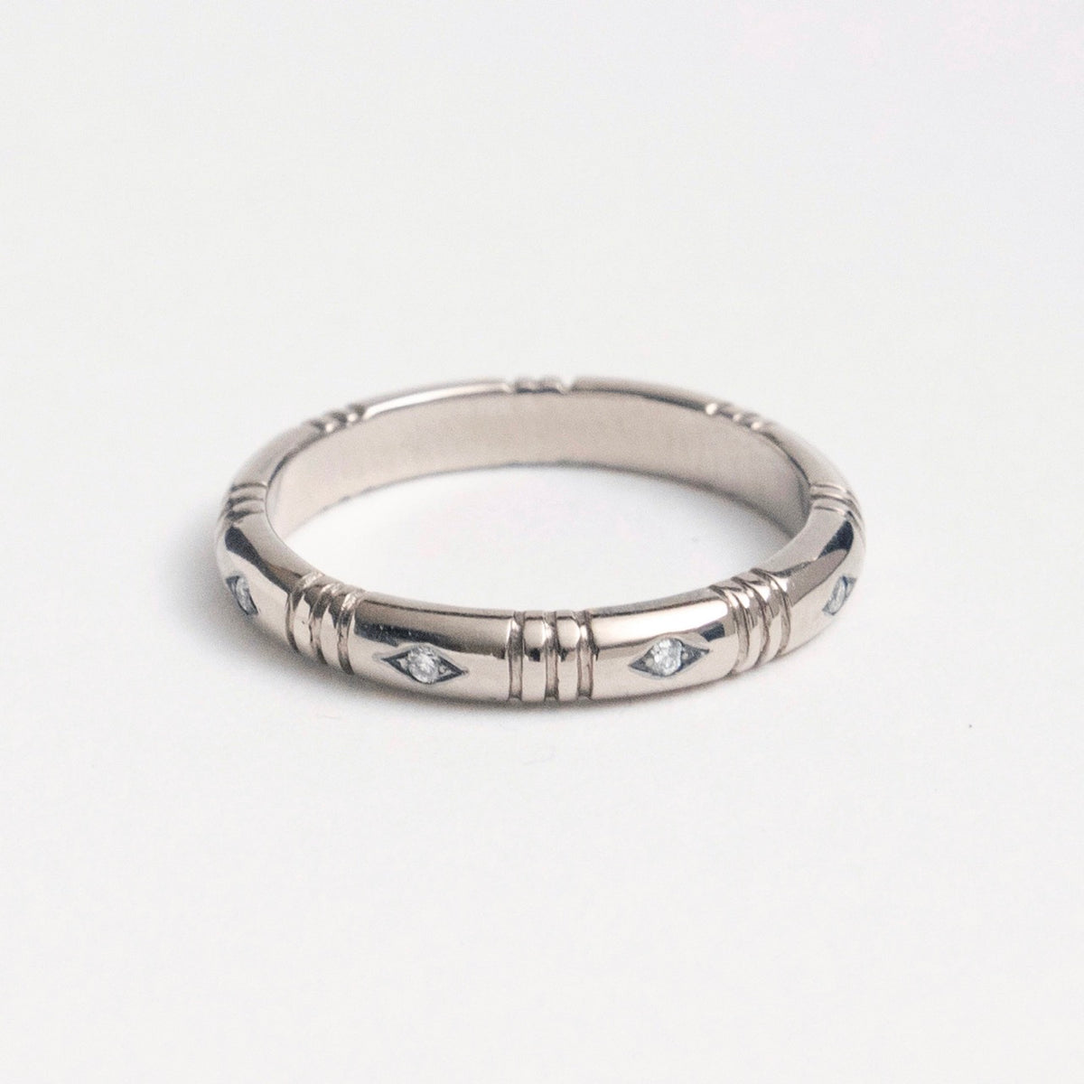 Banded ring in 18ct white gold featuring eight small diamonds set in a rhombus shape, designed for stacking.